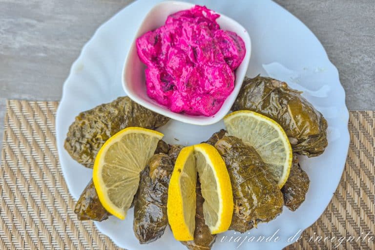 Plato de dolmas intercalados con rodajas de limón y acompañados de un plato de remolacha encurtida