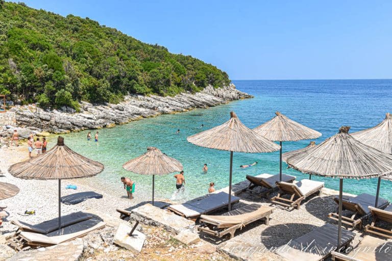 Pequeña playa de la península de Karaburun con sombrillas y gente bañándose en sus aguas color turquesa.