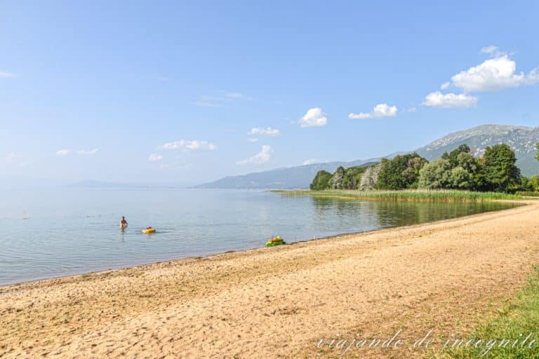 Un señor bañándose con un niño en la playa vacía del monasterio de San Naum