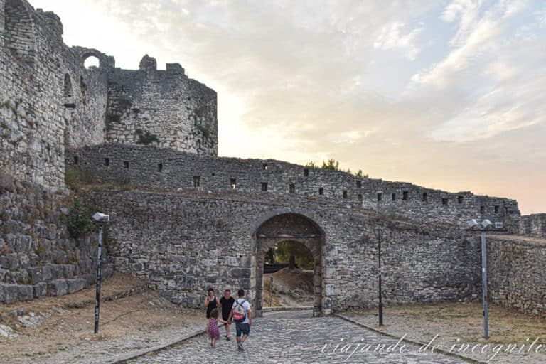 Varias personas salen y entran de la fortaleza de Berat al atardecer