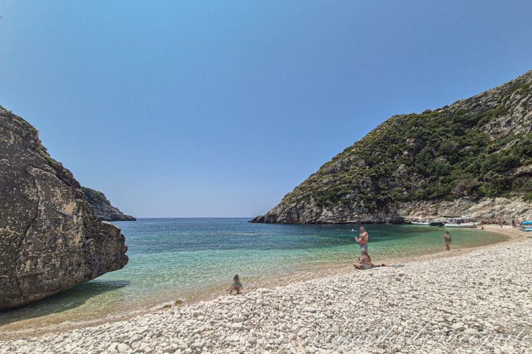 Tres personas están en la orilla del mar en la bahía de Grama, una de las mejores playas de Albania.