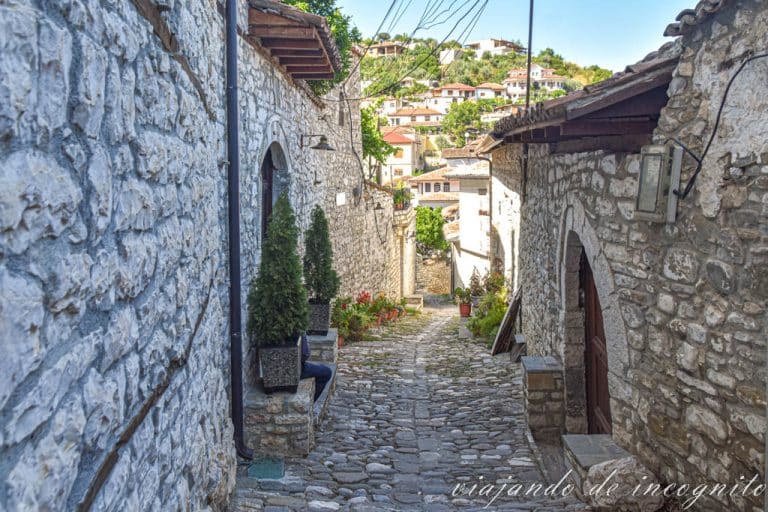 Calle empinada con casas de piedra de baja altura en Mangalem, Berat