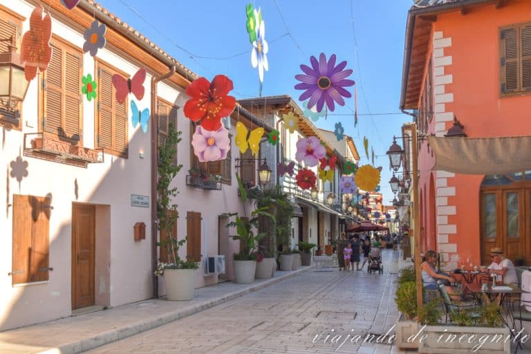 Algunas personas pasean por una de las calles del casco antiguo de Vlore decorada con flores y mariposas