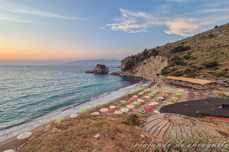 Playa Pasqyra con sombrillas en la arena y un búnker en primer plano