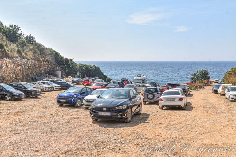 Varios coches aparcados en el parking gratuito de la playa Pulebharda al mediodía