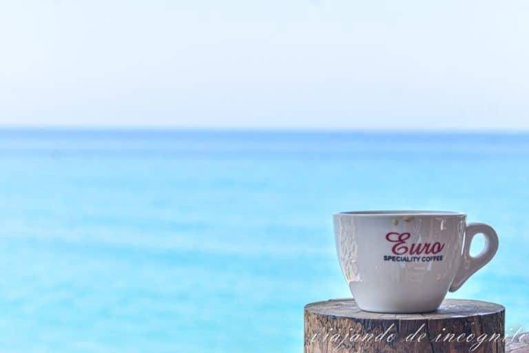 Taza de café contra un mar azul turquesa