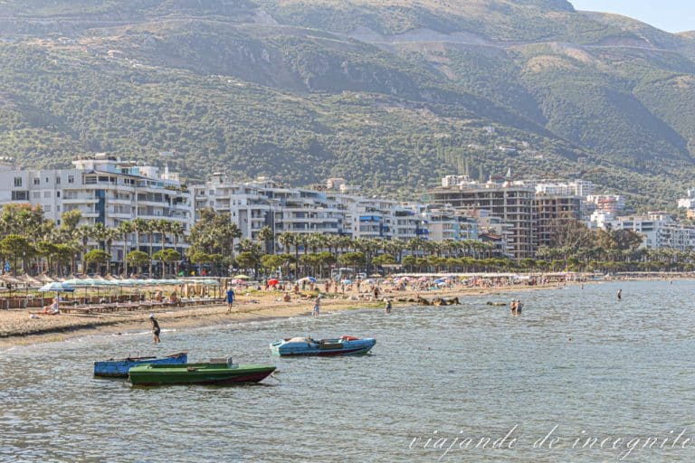 Vista panorámica de la playa Nueva de Vlore. Se ve gente bañándose y algunas barcas amarradas.