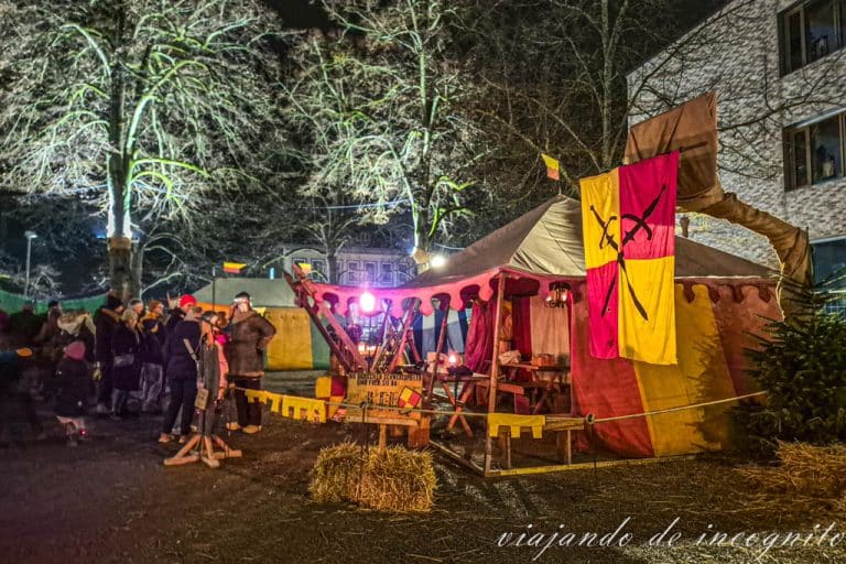 Varias personas se agrupan frente al campamento de espadachines de Baden en el mercado medieval de Durlach a la noche.