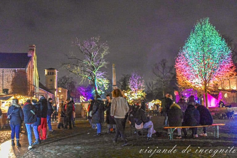 Varias personas disfrutan del mercadillo navideño en el palacio Britz al anaochecer.