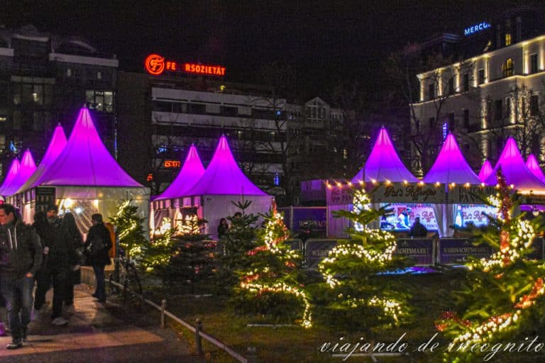 Pagodas blancas iluminadas en rosa del mercado navideño en el KaDeWe al anochecer.