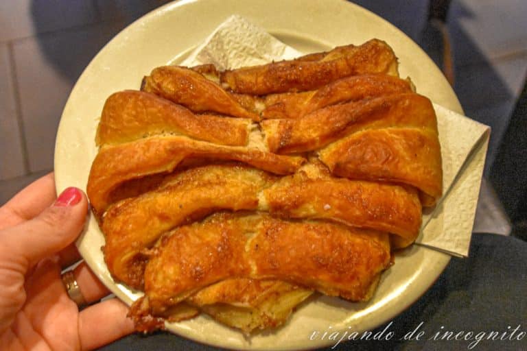 Una mano sujeta un plato blanco donde hay un franzbrötchen