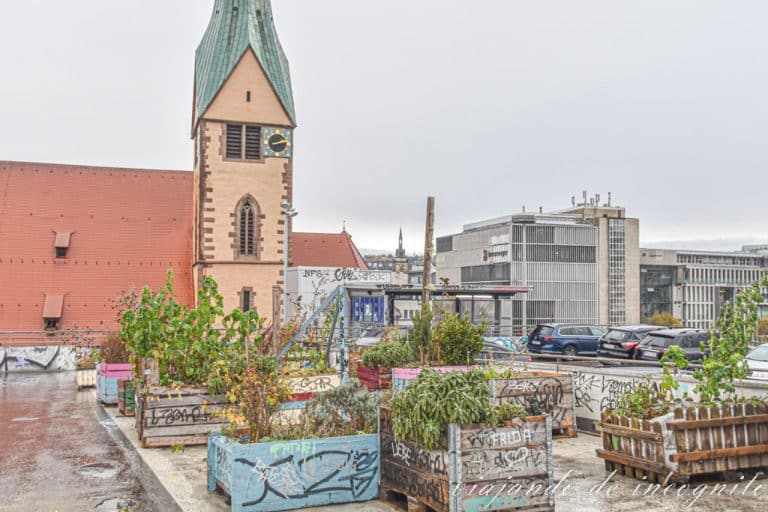 Macetas de madera con plantas en la última planta de un aparcamiento frente a la torre de la Leonhardskirche