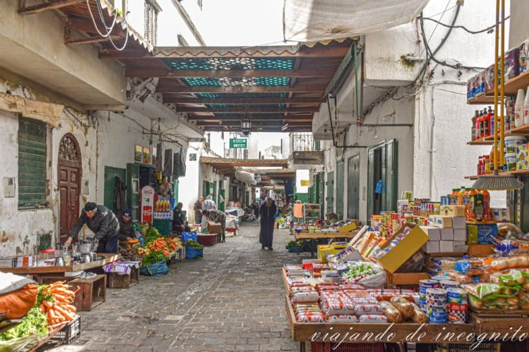 Un hombre camina por la calle Ayun en la Medina de Tetuán entre puestos de comida y otros productos.