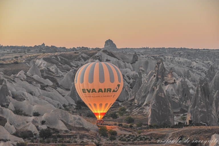 Globo de eva air a punto de despegar, rodeado de formaciones rocosas al amanecer. Volar en globo es una de las actividades que hacer en Capadocia