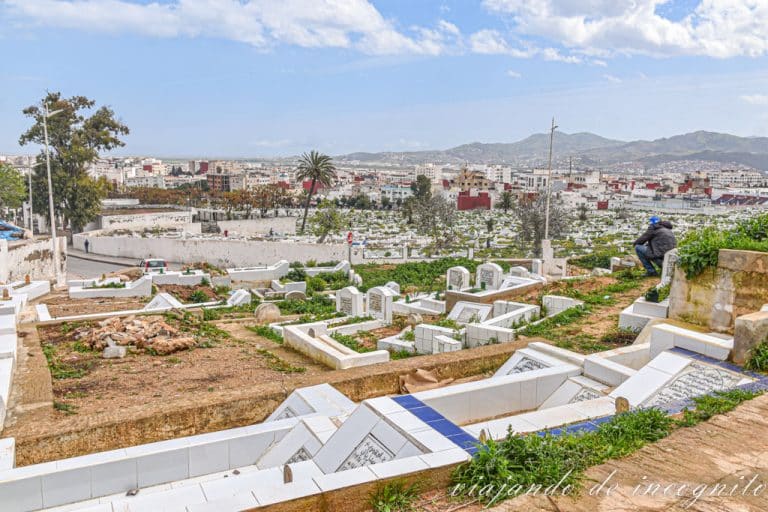 Un hombre está sentado junto a algunas tumbas blancas del cementerio musulmán de Tetuán.