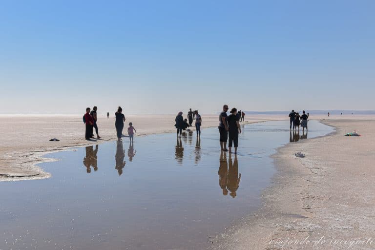 Gente reflejada en el agua de un charco del lago Tuz mientras se moja los pies