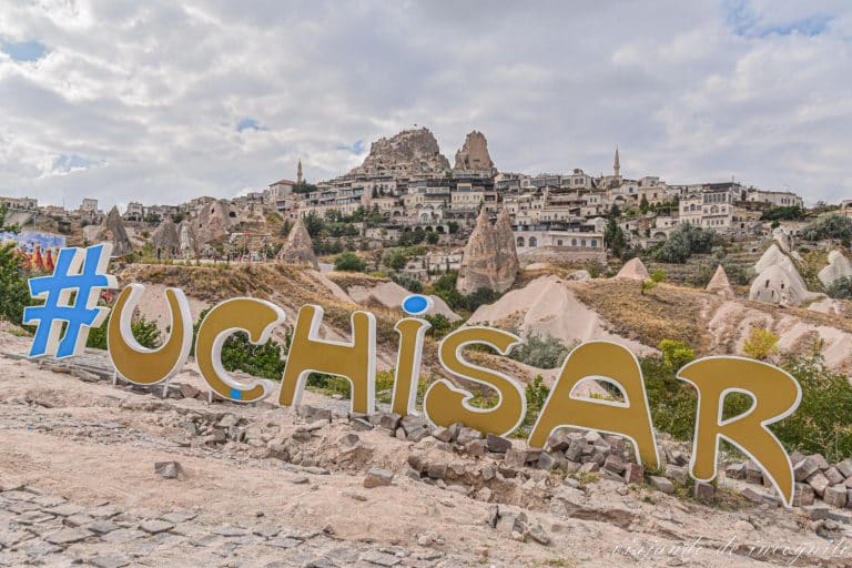 Letras de Uchisar en color dorado con las vistas de la ciudad al fondo