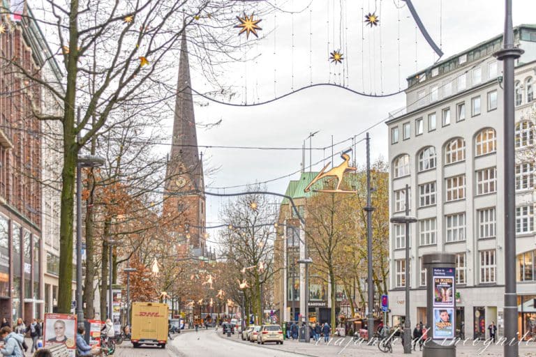 La calle comercial de Hamburgo Monckebergstrasse decorada para navidad y con la torre de la iglesia de San Pedro al fondo.