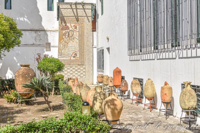 Entrada al museo donde se va una parte del jardín con ánforas romanas y un fragmento de un mosaico.