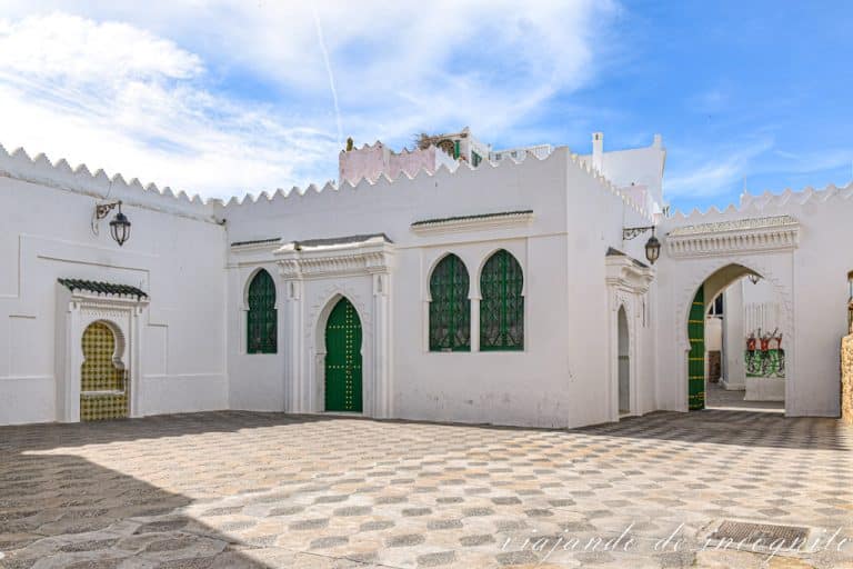 Una de las parte del palacio Raissouni, donde se ven puertas y ventanas verdes y una fuente decorada con azulejos.