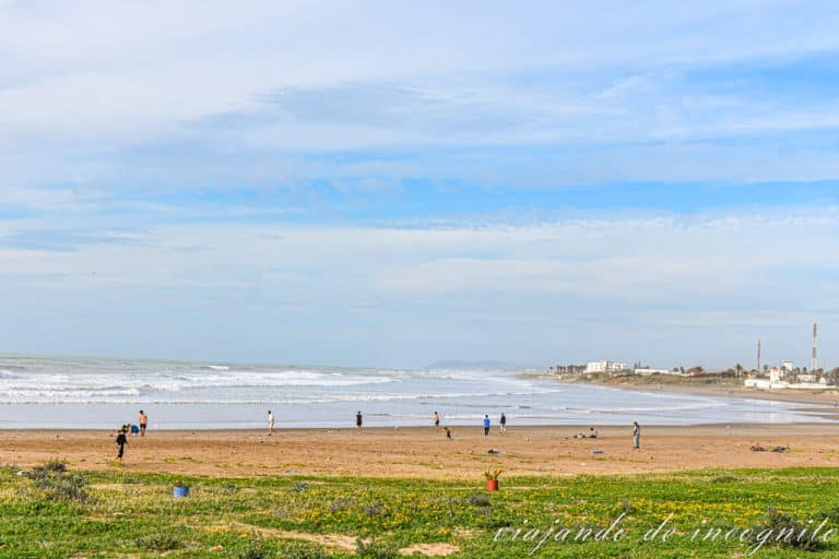 Gente paseando y jugando al balón en la playa de la ciudad de Asilah.