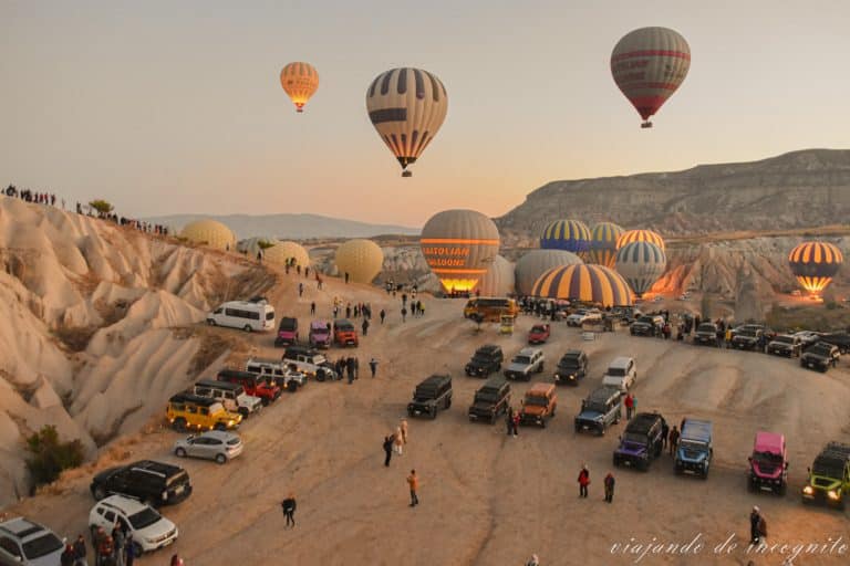 Muchos coches y mucha gente viendo como van despegando los globos al amanecer. Volar en globo es una de las actividades que hacer en Capadocia