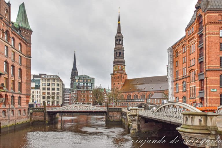 Vista de Santa Catalina desde uno de los puentes que lleva a la Speicherstadt de Hamburgo. Al fondo se ve la torre de San Nicolás.