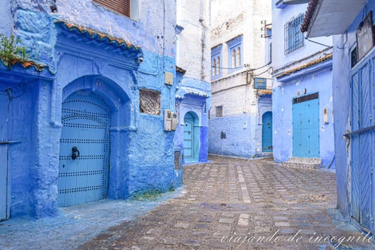 Una calle de Chefchaouen de casas blancas y azules y puertas azules.
