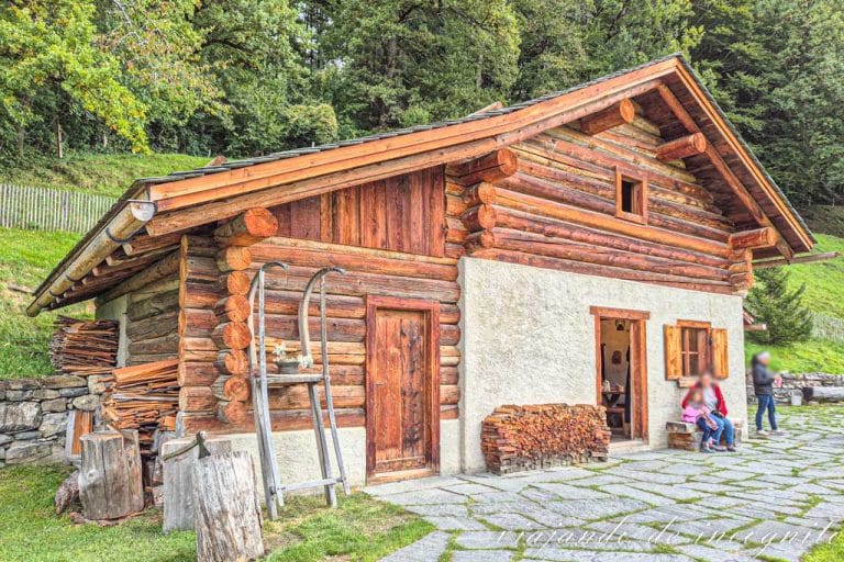 Una madre y su hija están sentadas en un banco frente a la casa de los Alpes de Heidi.