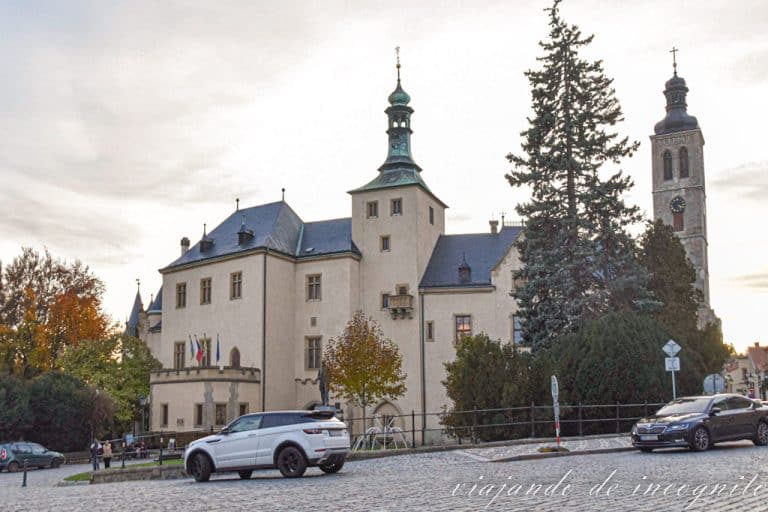 Un coche blanco pasa frente a la Corte Italiana, al fondo se ve la torre de la iglesia de Santiago.