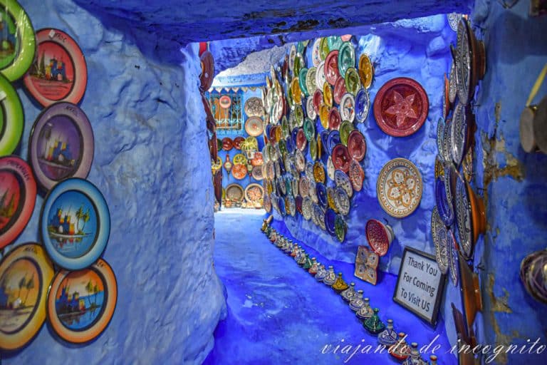 Pasillo de entrada decorado con platos de colores a la petite maison bleue, una tienda de artesanía en Chefchaouen.