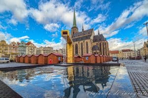 Fuente de la plaza principal de Pilsen en funcionamiento y con la iglesia reflejada en sus aguas.