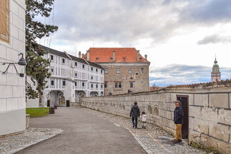 Un padre y una hija van de la mano hacía el puente del Manto del castillo de Cesky Krumlov
