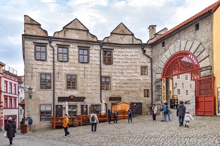 Varias personas caminan frente a la puerta de entrada del castillo de Cesky Krumlov.