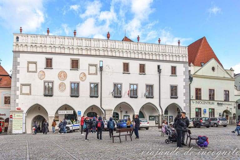 Varias personas se encuentran frente al ayuntamiento de color blanco de Cesky Krumlov