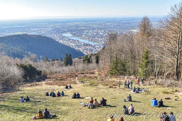 Varias personas están sentadas en lo alto del Königstuhl disfrutando de las vistas.