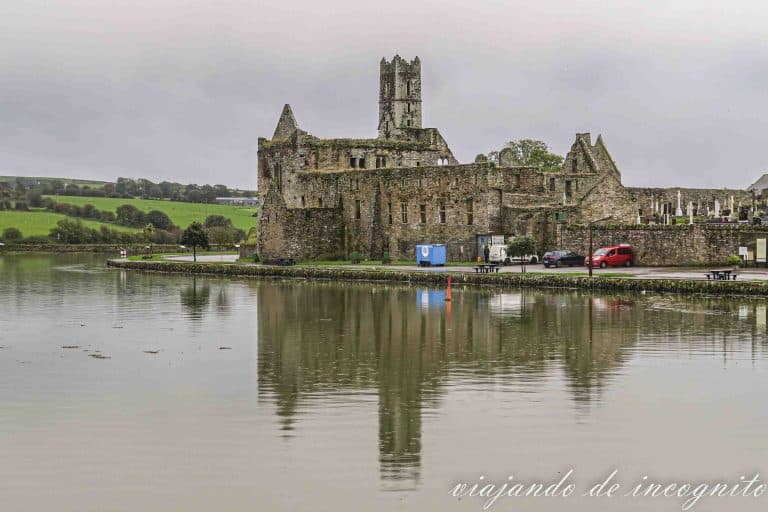 Abadía de Timoleague reflejada en el agua en un día gris y lluvioso.