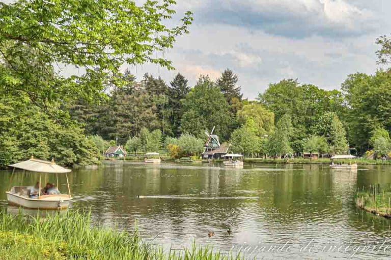 Una barca de la atracción Gondoletta recorre el lago del parque Efteling. Al fondo se ve un molino.