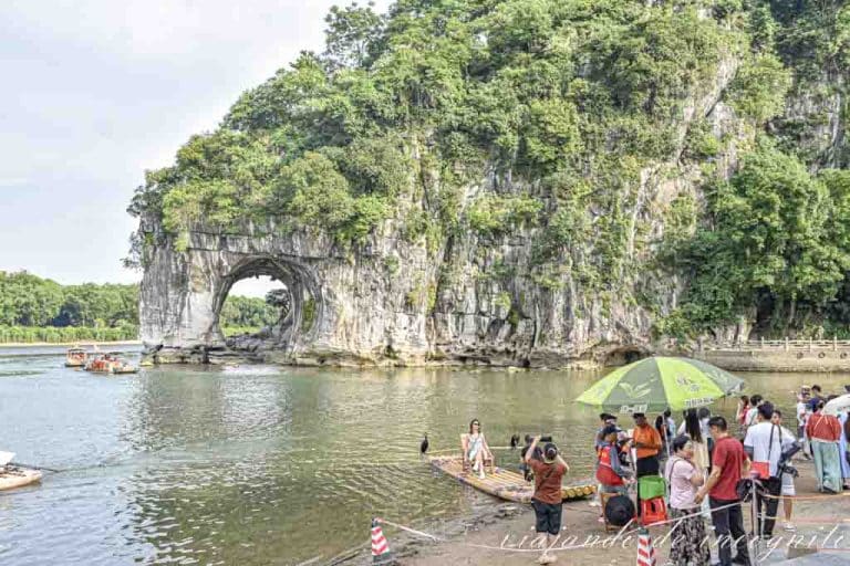 Varias personas se sacan fotos con la trompa del elefante de Guilin de fondo.