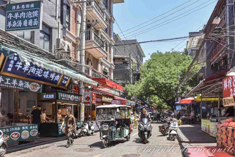 Calle del barrio musulmán con motos, carros y gente andando por ella.