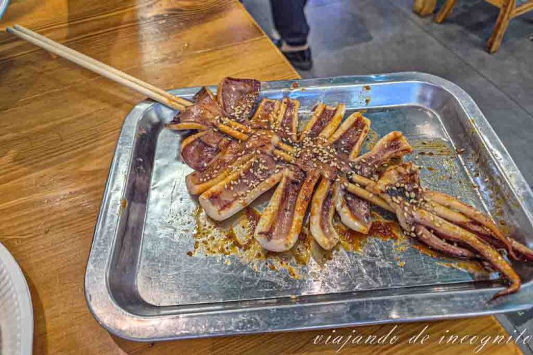 Calamar sazonado y pinchado en un palo sobre una bandeja.