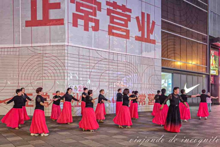 Grupo de chinas bailando con faldas rojas y camisetas negras.