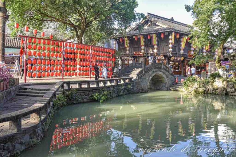 Rincón de la calle Jinli donde hay un puente reflejado en el agua y decorado con lamparas chinas de color rojo.