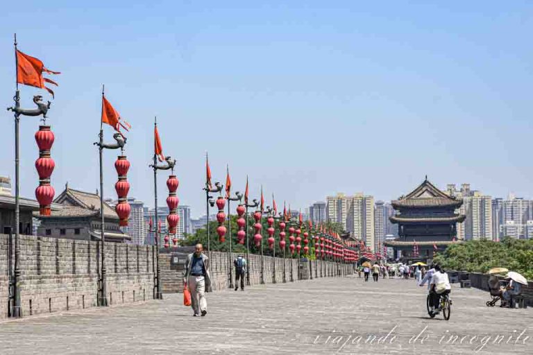 Personas a pie y en bicicleta pasean por la muralla china de Xian, que está decorada con faroles rojos.