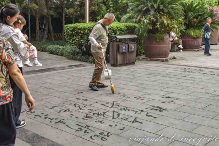 Hombre escribiendo en el suelo del people´s park con agua.