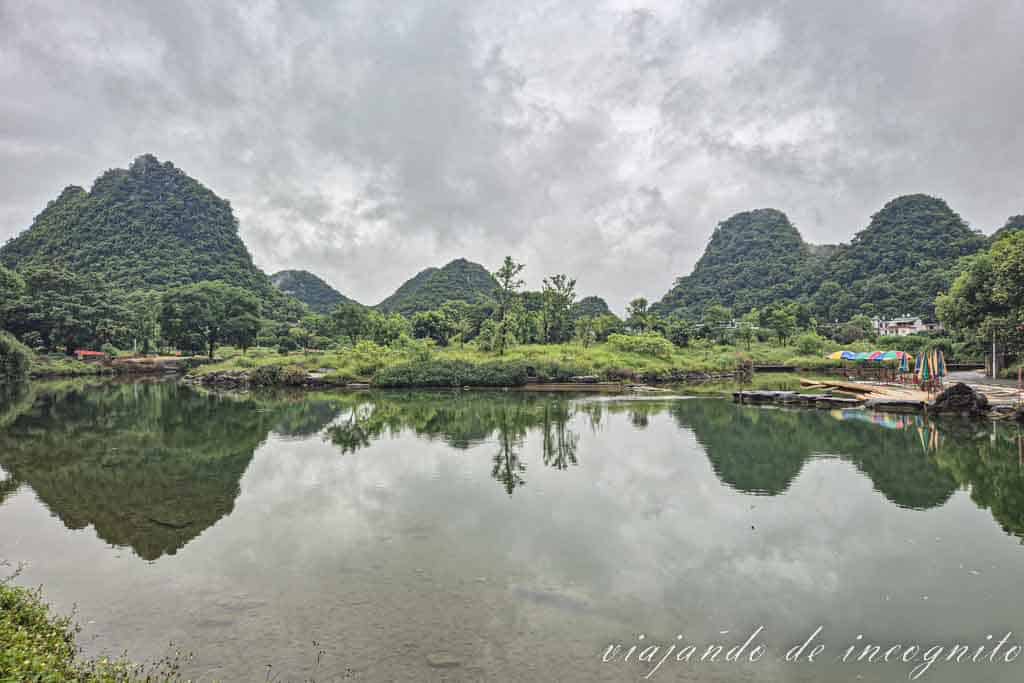 Paisaje de montañas alrededor del puente Fuli. Estas se reflejan en el agua del río.