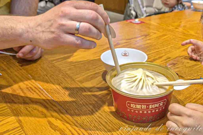 Dos personas sorben con pajita de un Xialongbao grande.