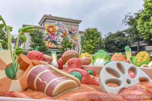 Monumento al Hot pot en Qianmen. Al fondo se ve una cara hecha con laternes que decora la fachada de un edificio.