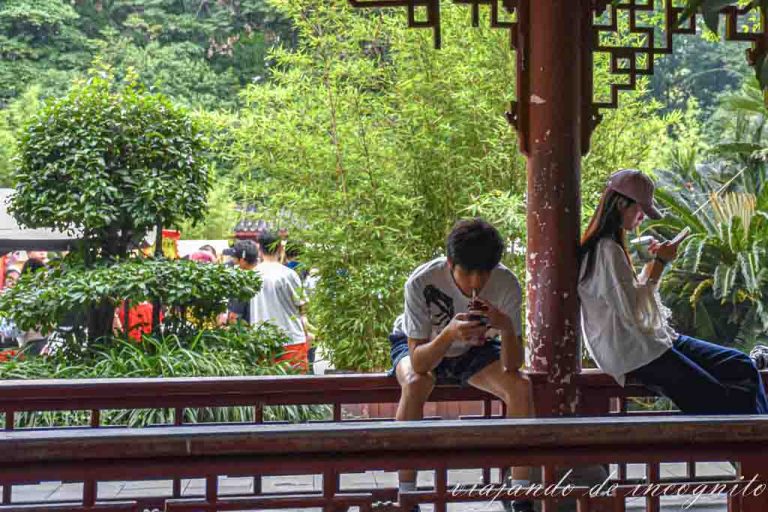 Dos jóvenes miran al móvil sentados en una barandilla del Peoples park en Chengdu.