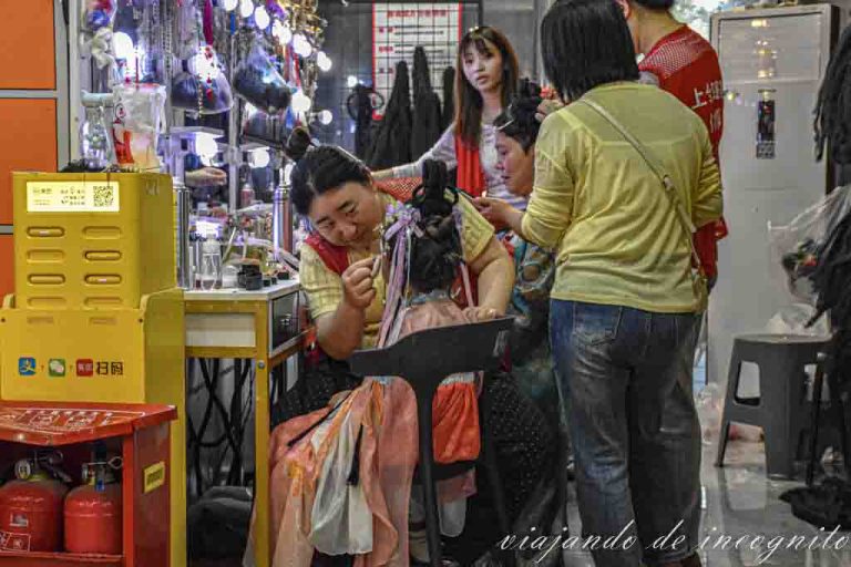 Una mujer maquilla a una niña en una tienda de Xian para una sesión de fotos en traje tradicional.
